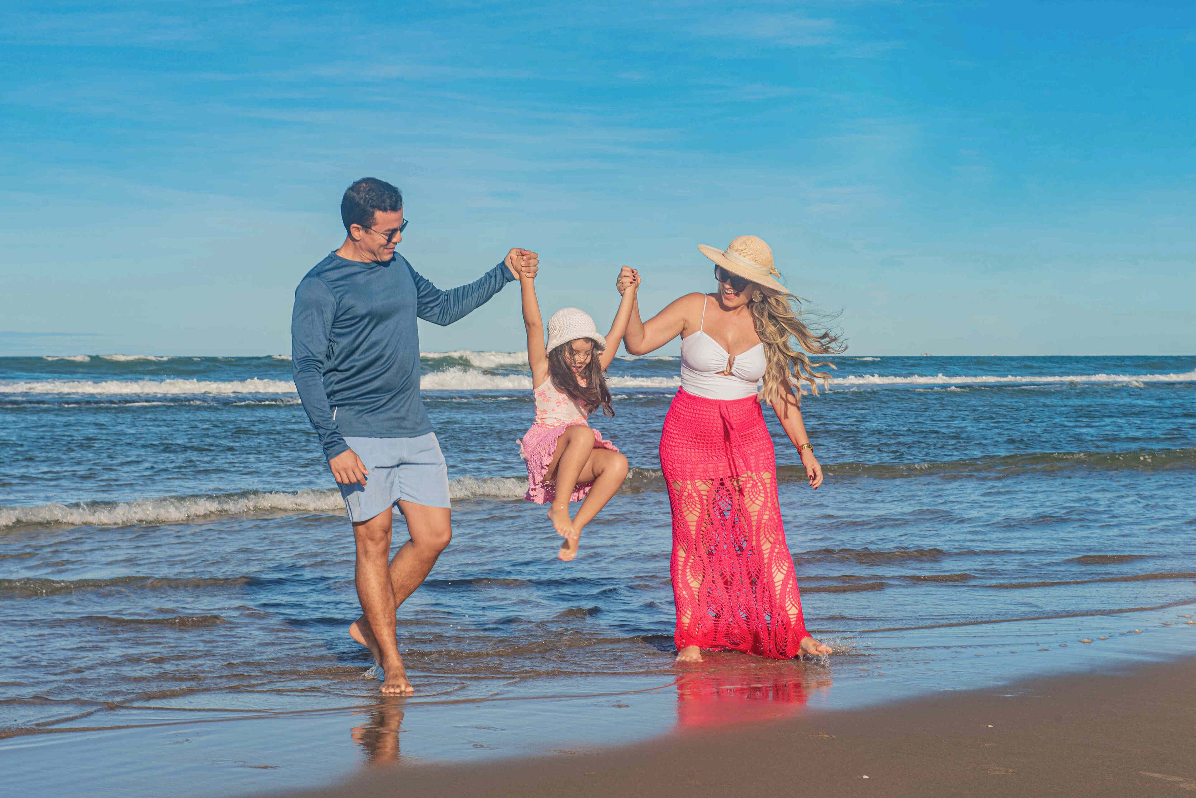 Una familia caminando sobre la playa con el océano al fondo.