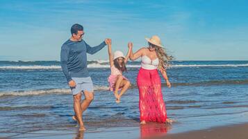 Una familia caminando sobre la playa con el océano al fondo.
