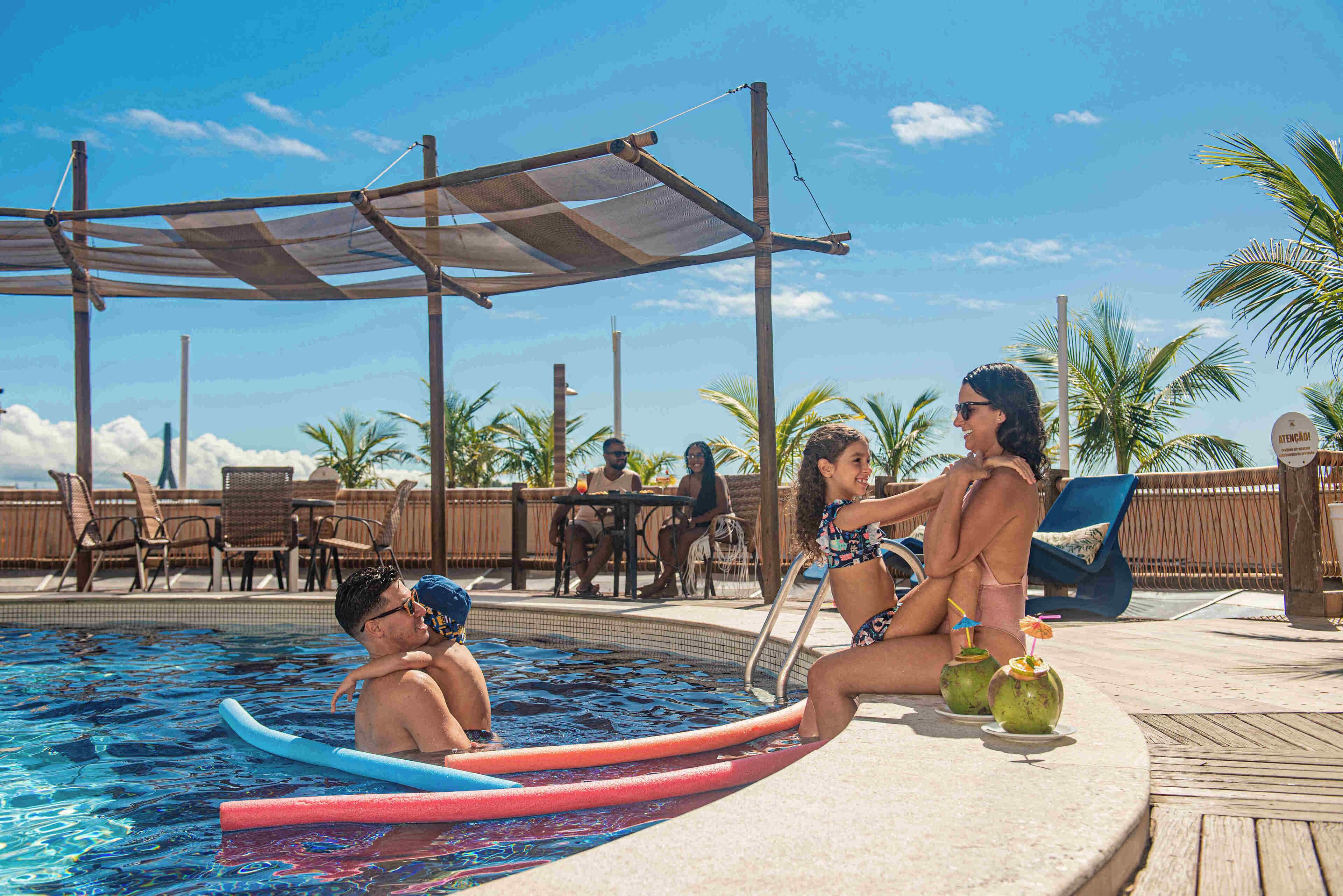 Ein Poolbereich mit Liegestühlen, einem schattigen Platz und tropischer Umgebung.
