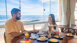 A dining table with breakfast items and a view of the ocean. - Opaba Praia Hotel (Ilhéus)