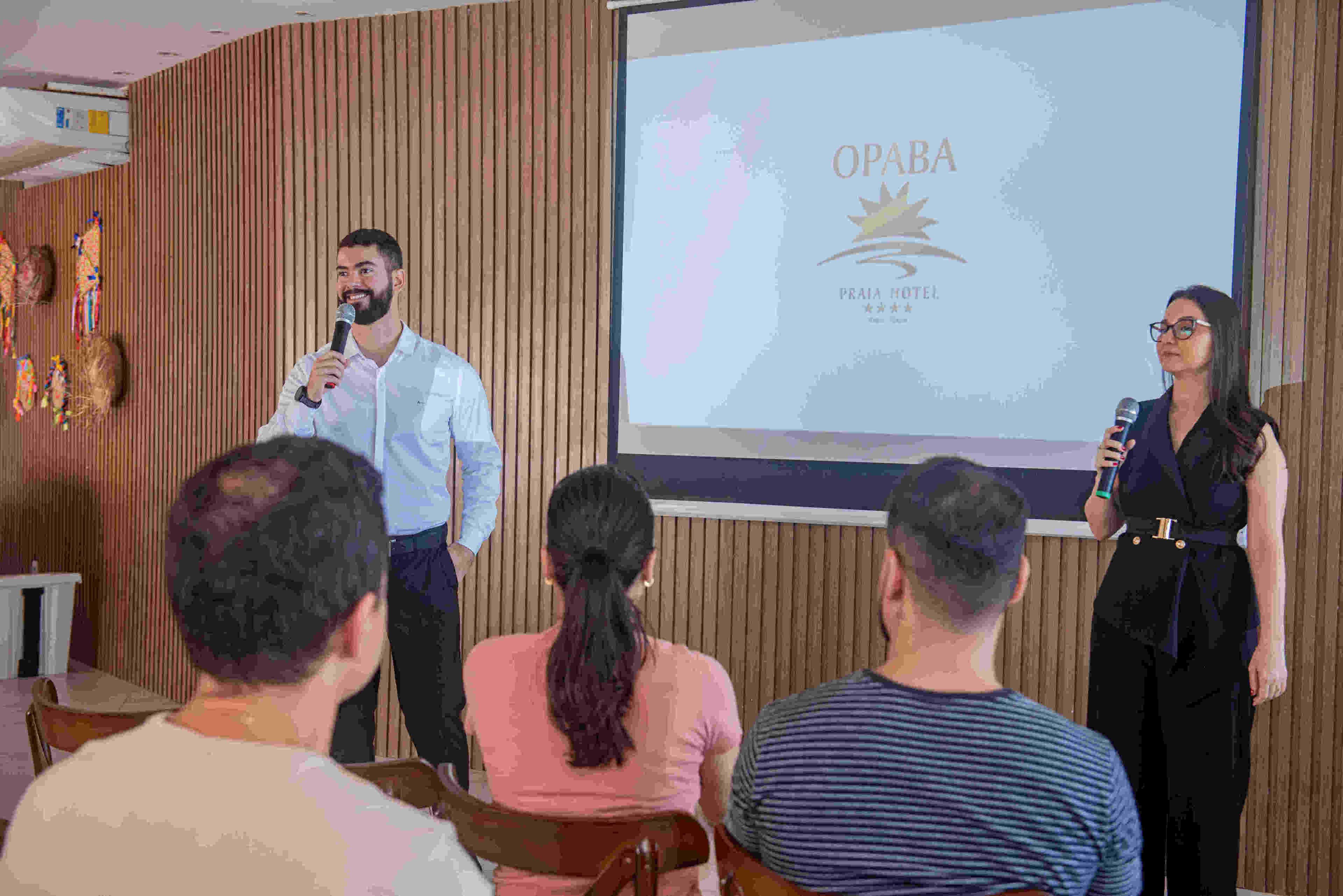Presentació en una sala amb un mur de fusta i una pantalla que mostra el logotip d'OPABA.