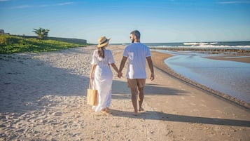 Um casal caminhando por um caminho de areia com vista para o oceano.