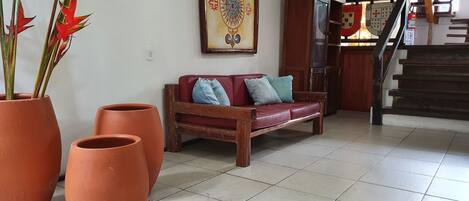 A living room with a red sofa, two large terracotta pots, and a decorative wall piece.