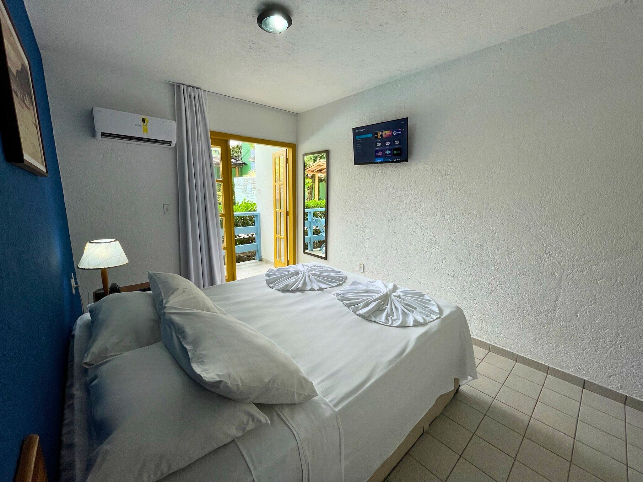 A bedroom with a bed, a TV, and an air conditioning unit.