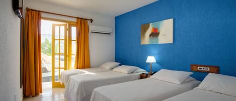 A hotel room with two beds, a blue wall, a painting, and a window with curtains.