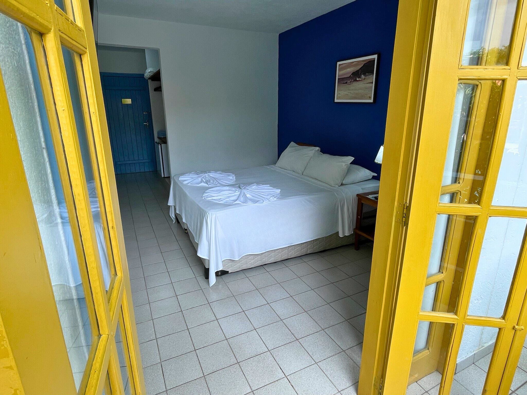 Quarto com uma cama, parede azul e porta com detalhes amarelos.