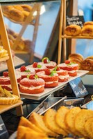A bakery display with various pastries and desserts, including red velvet cakes and fresh berries.