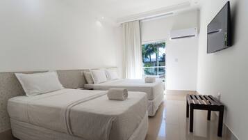 Una habitación de hotel con dos camas, televisión y balcón con vistas.