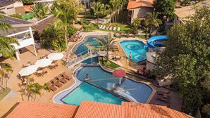 A resort with multiple swimming pools, a water slide, and sun loungers.