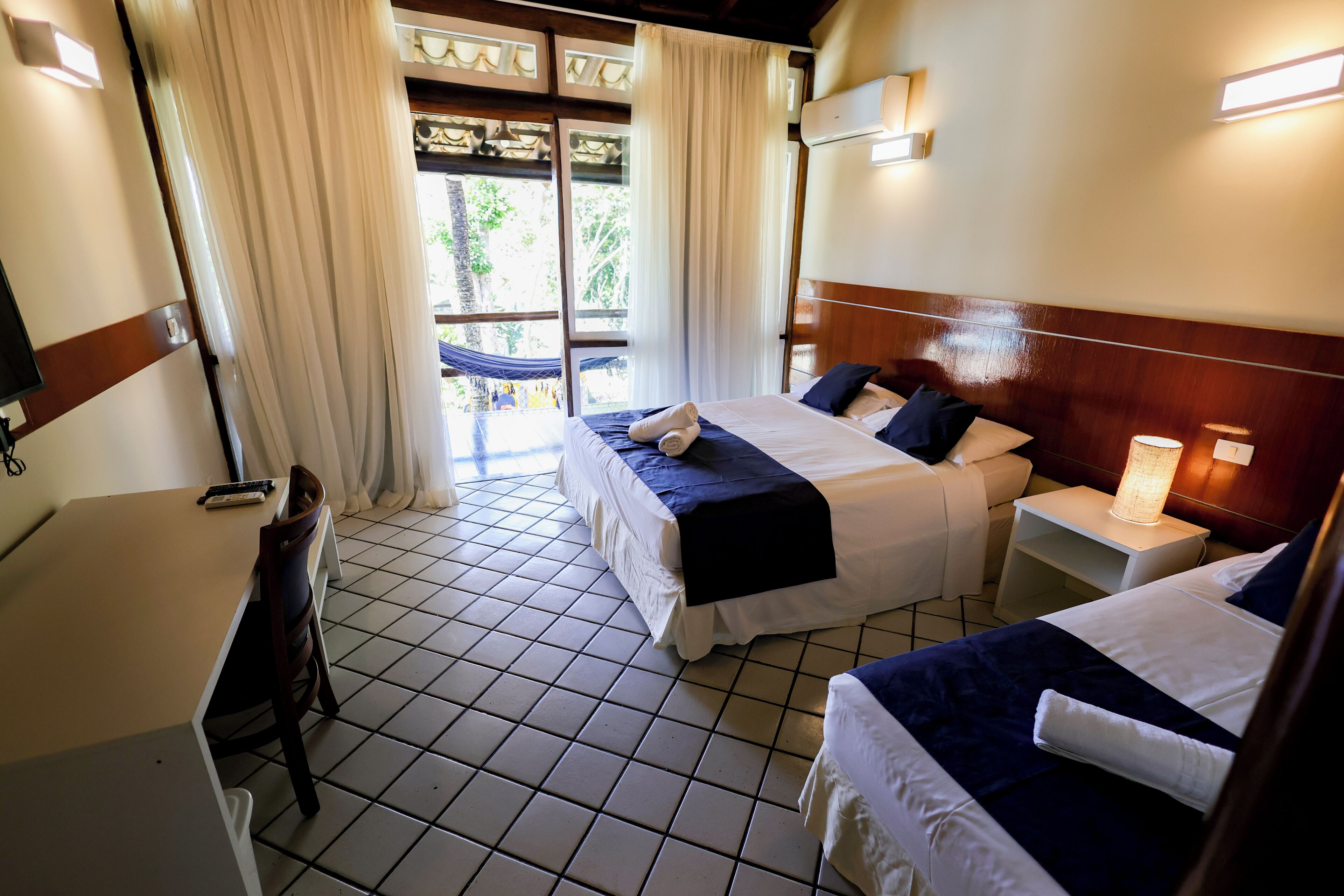 Habitación de hotel con dos camas, un escritorio y vistas al exterior.