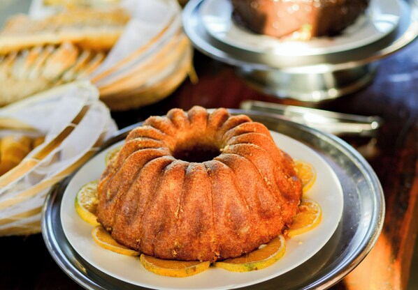 A bundt cake on a plate with lemon slices. - Pousada Pontal da Ferradura (Búzios)