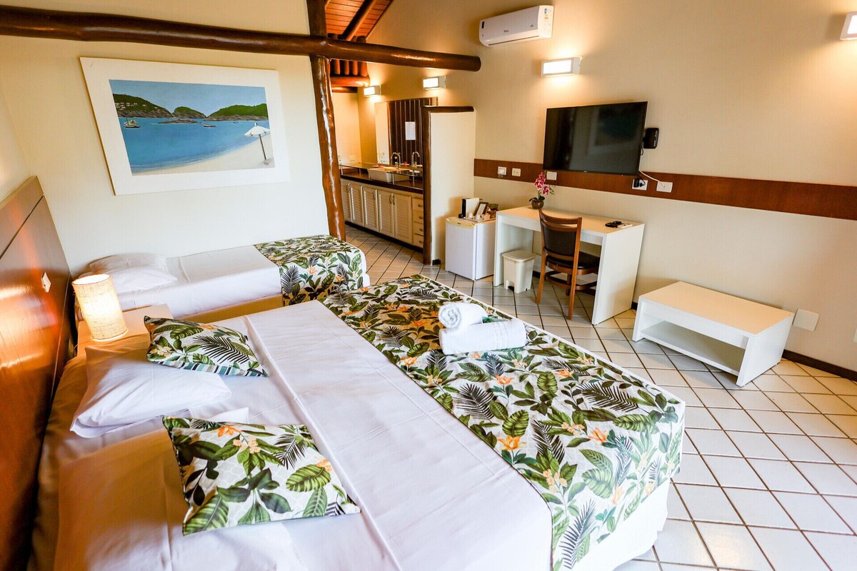 Habitación de hotel con dos camas, un escritorio, un televisor y un cuadro de una playa.