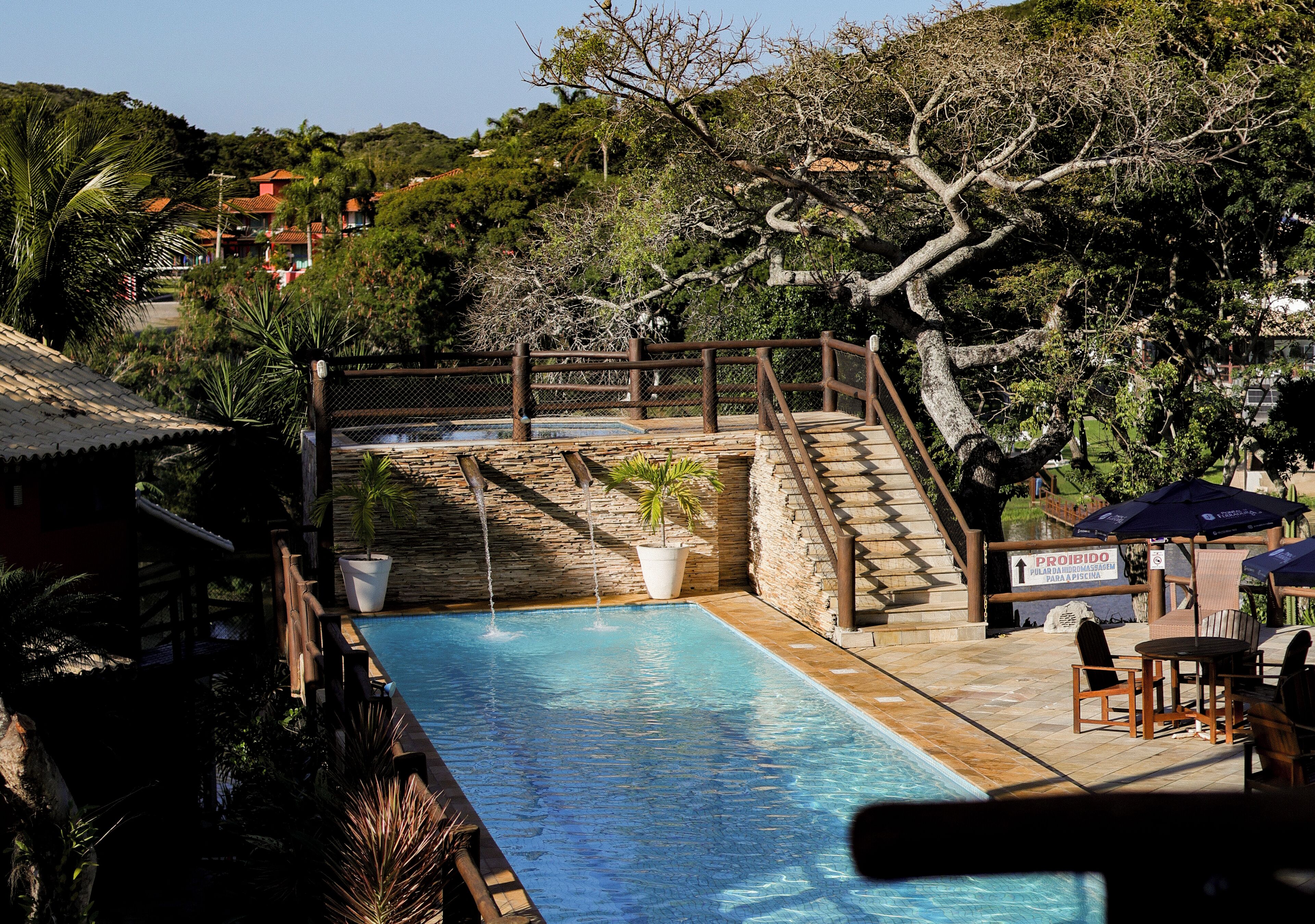 A swimming pool with a wooden deck, a stone wall, and a sign indicating no swimming.