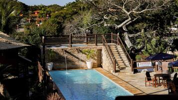A swimming pool with a wooden deck, a stone wall, and a sign indicating no swimming.