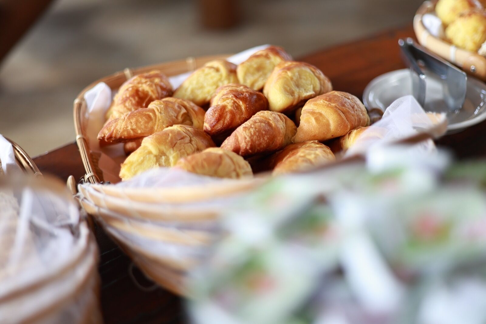 A basket of assorted pastries, including croissants and other baked goods, on a table.
