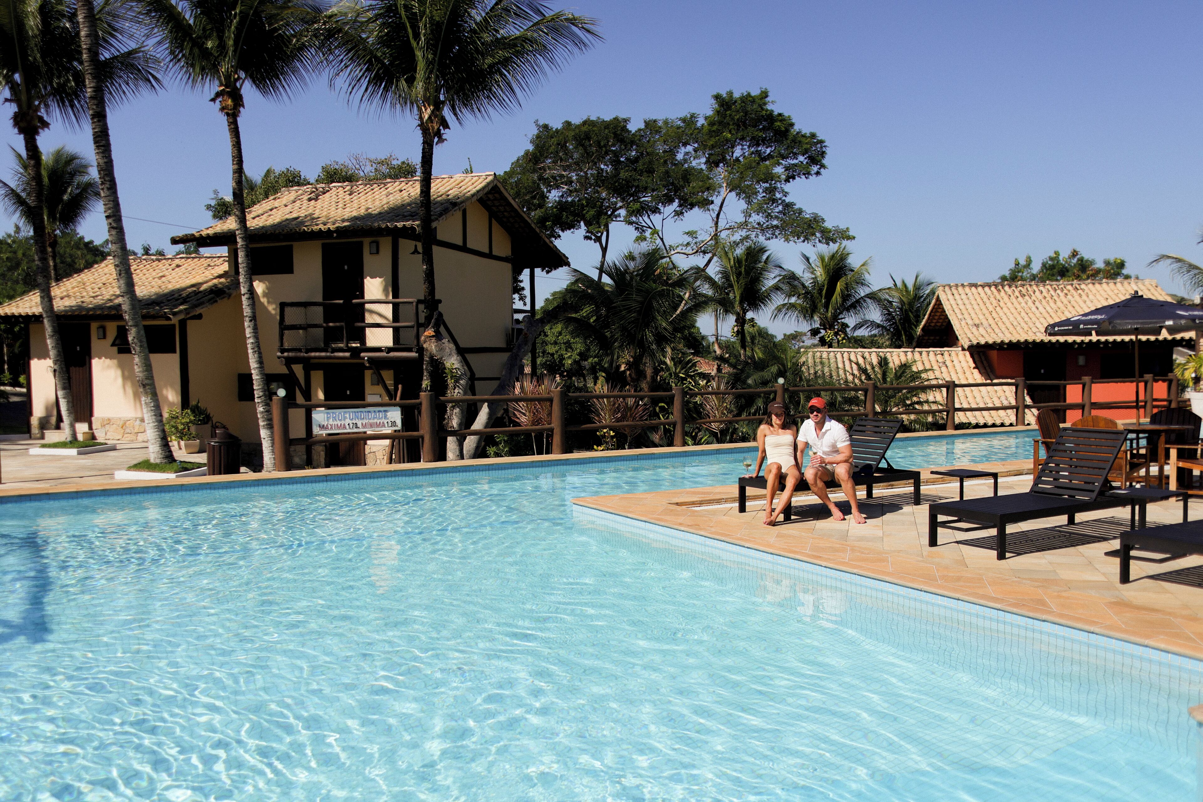 A swimming pool with lounge chairs and palm trees.