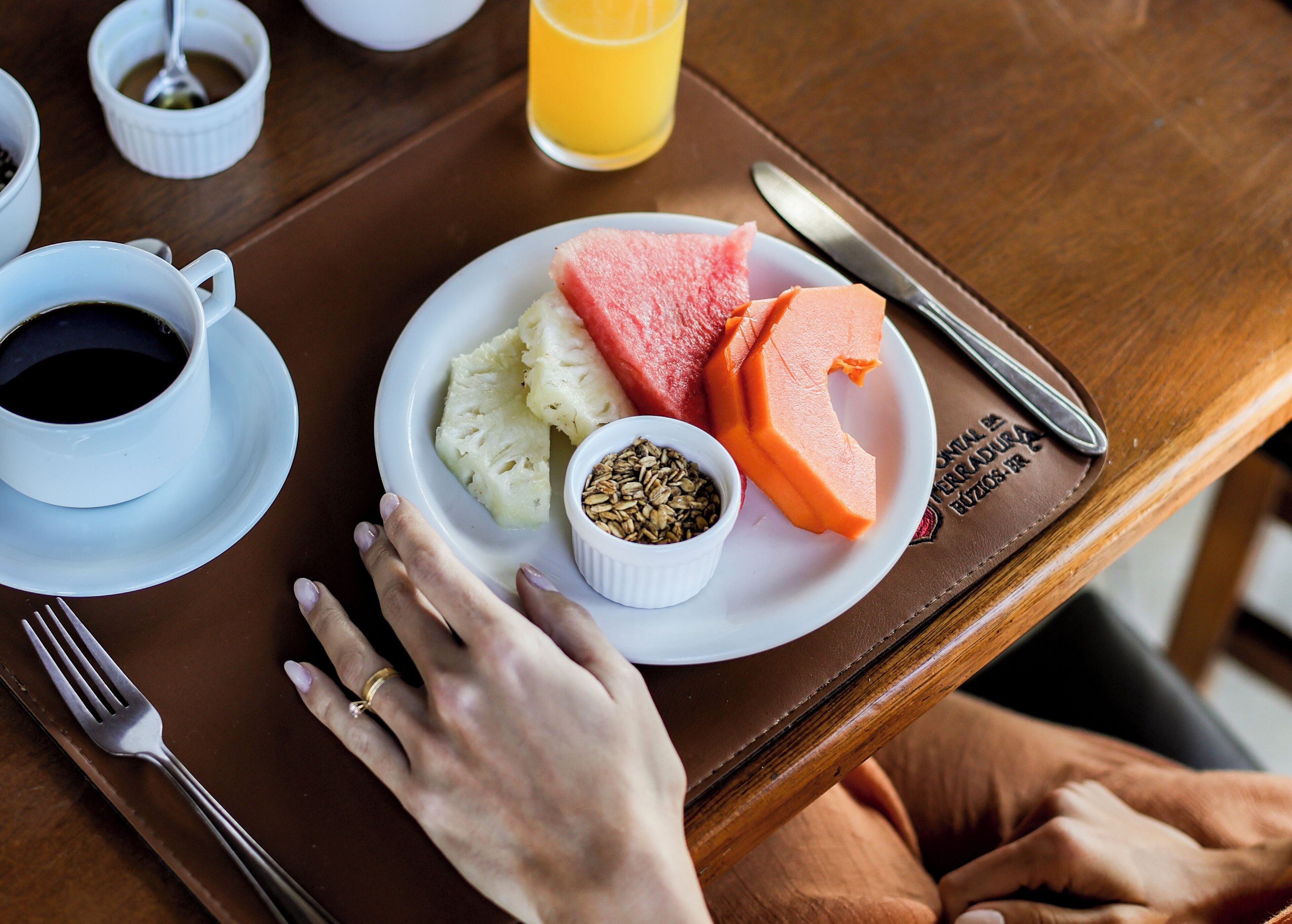 A breakfast tray with a plate of food, a cup of coffee, and a glass of orange juice on a wooden table.