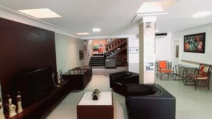En moderne lobby med et fladskærms-tv, sorte sofaer, et sofabord og en trappe, der fører til en etage ovenover.