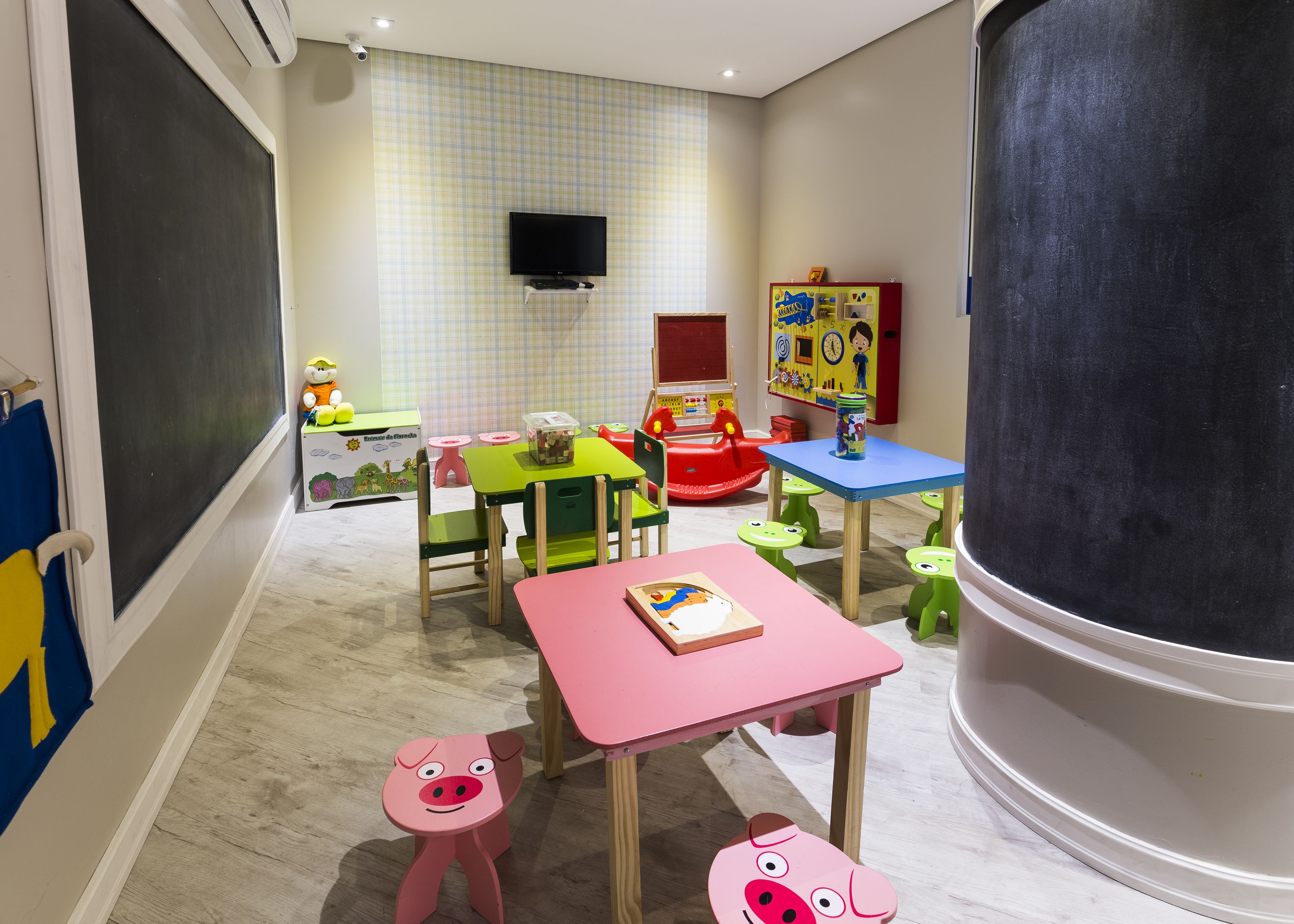 Un cuarto de juegos infantil con mobiliario colorido, una pizarra y juguetes educativos.