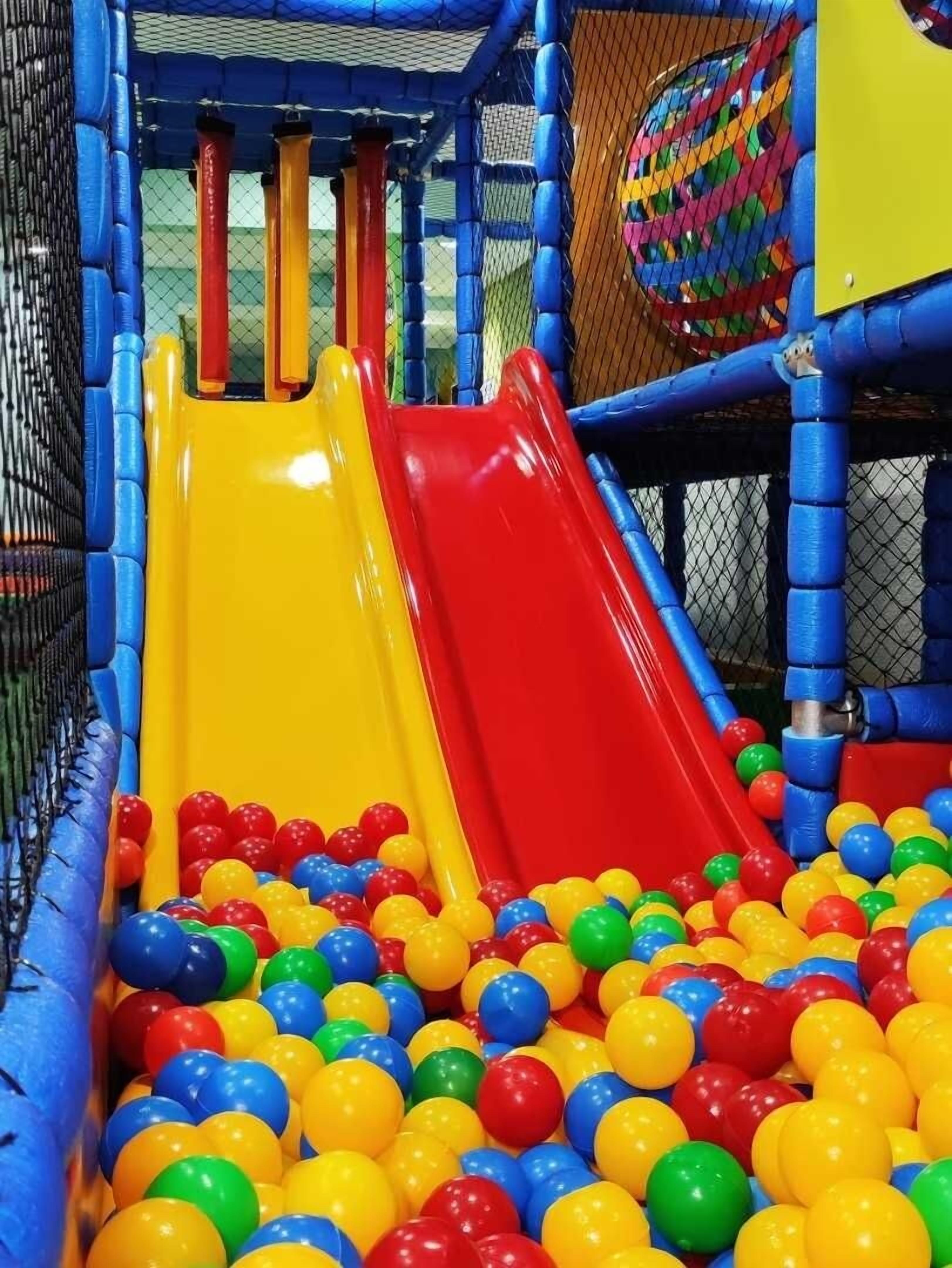 A play area with two slides and a ball pit filled with multicolored balls.