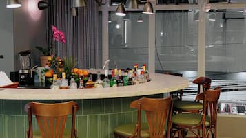 A modern kitchen with a curved island, bar stools, pendant lighting, and a view of the city through large windows.