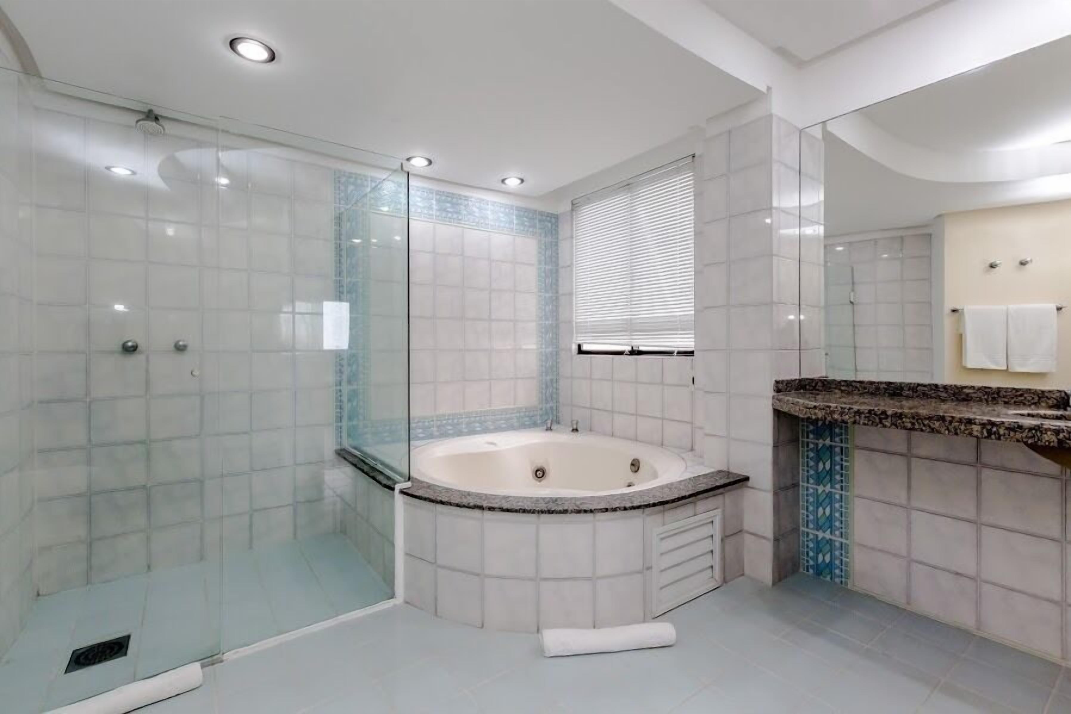A modern bathroom with a glass-enclosed shower, a freestanding bathtub, and a vanity with a granite countertop.