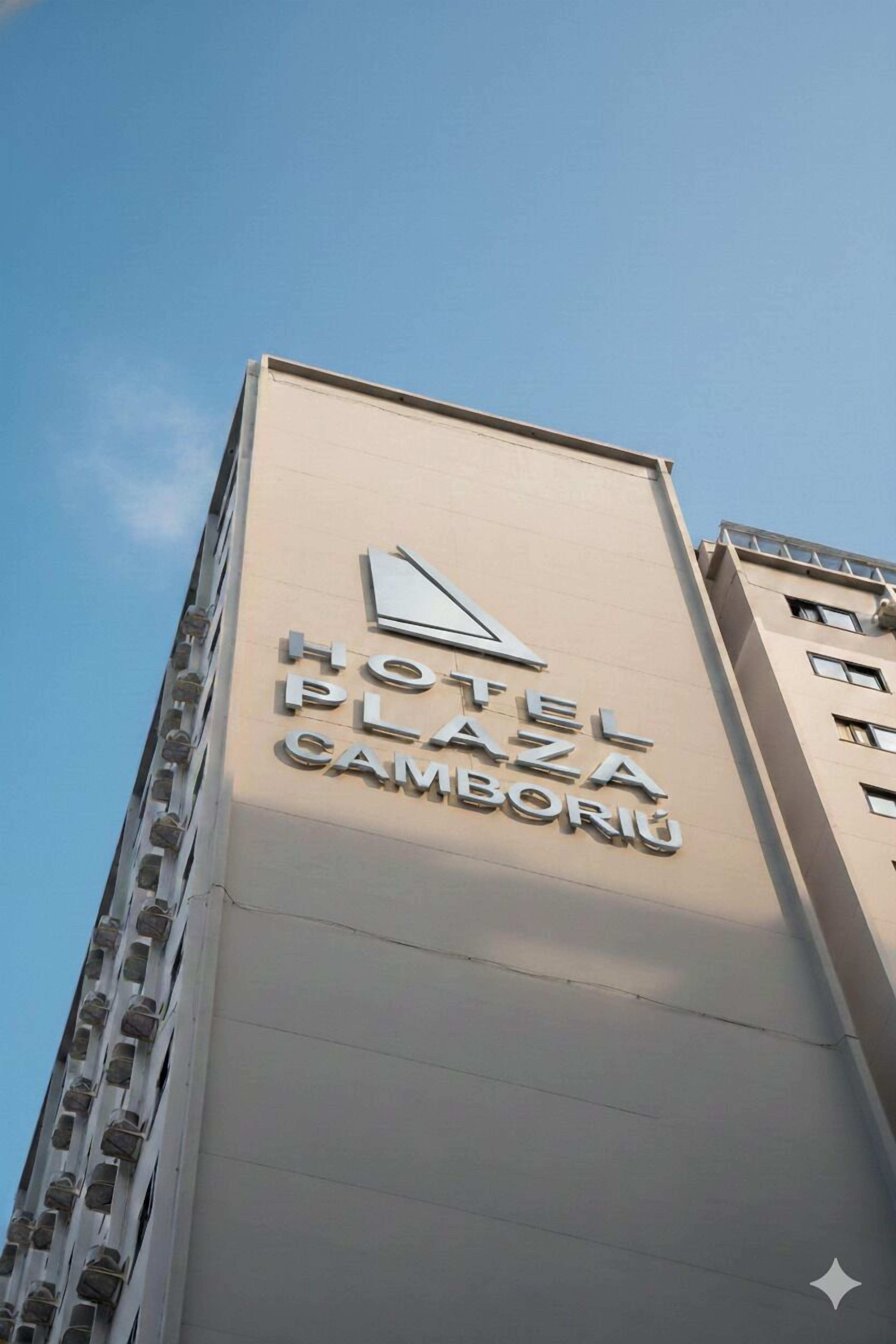 A hotel sign with the name "HOTEL PLAZA CAMBORIU" on a building.