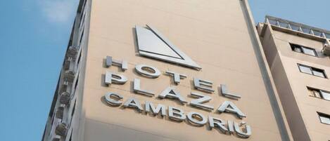 Señal de hotel con el nombre 'HOTEL PLAZA CAMBORIU' en un edificio.
