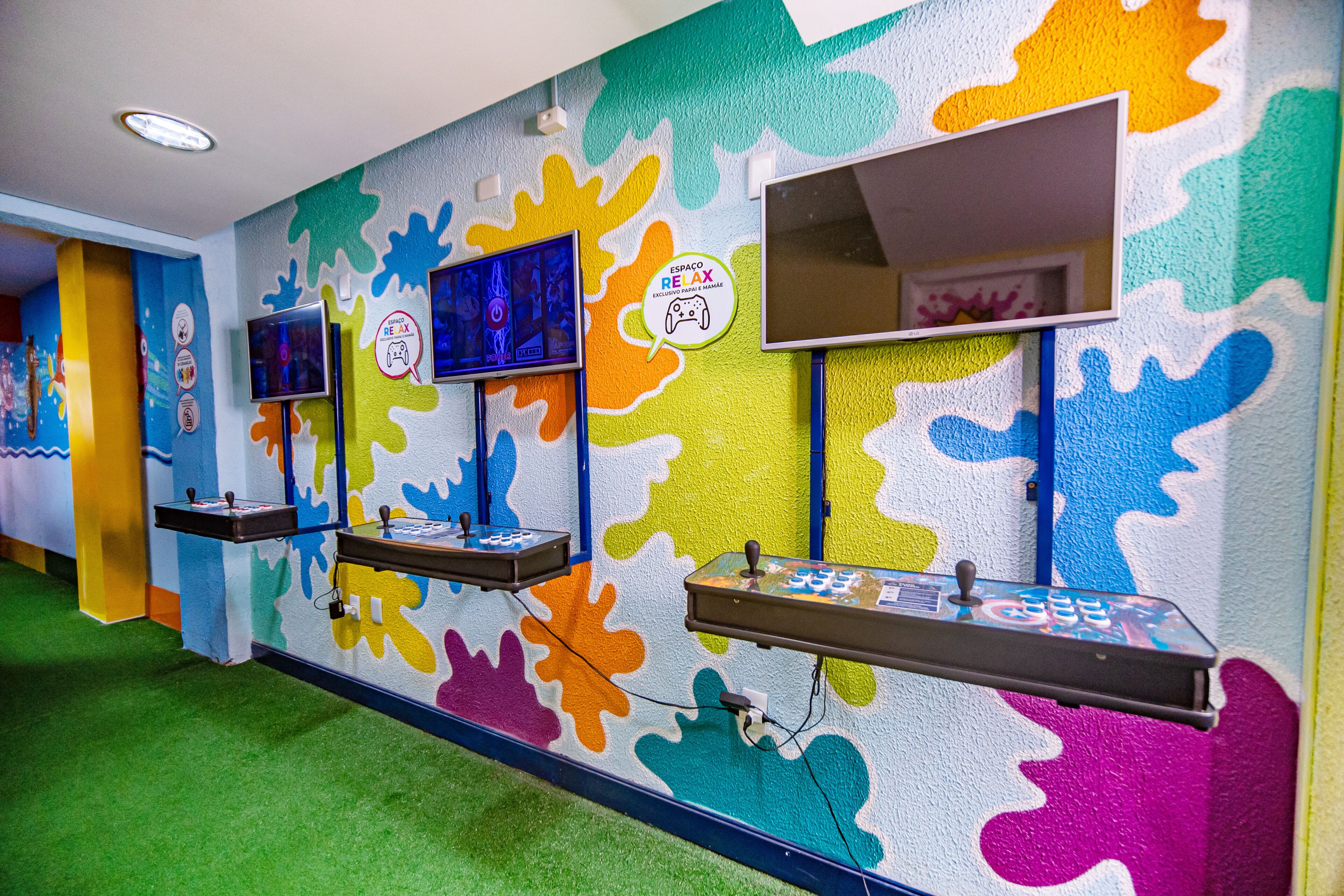 A colorful wall with abstract patterns and two arcade machines.