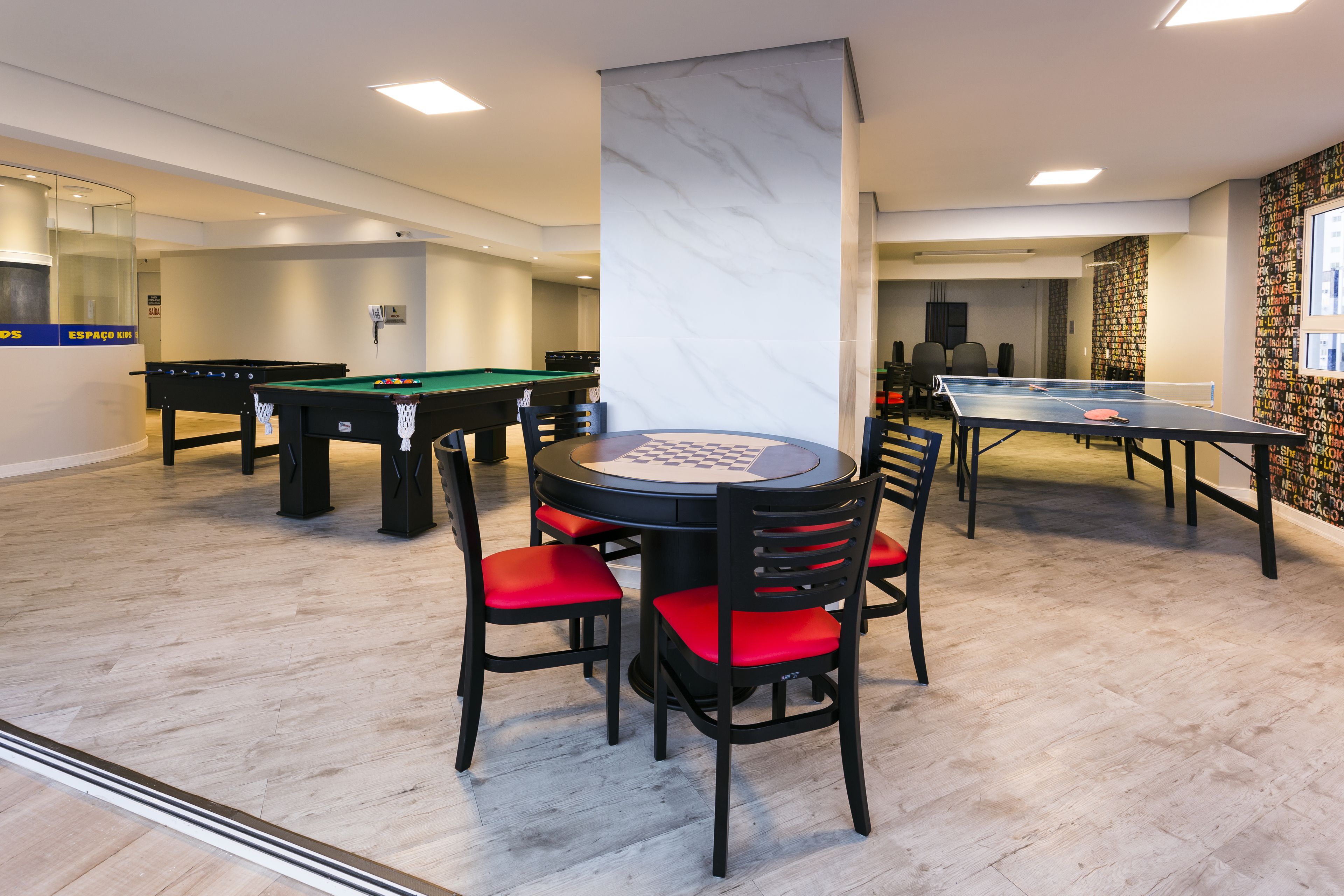 A pool table, a ping pong table, and a billiards table in a well-lit indoor space with a marble pillar.