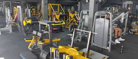 Un gimnasio con diversas máquinas de ejercicio, incluyendo una estructura para sentadillas y una prensa de banca.
