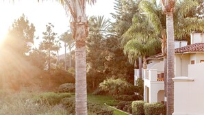 A landscaped garden with palm trees, a pathway, and a building with a tiled roof. - Four Seasons Residence Club Aviara, North San Diego (Carlsbad)