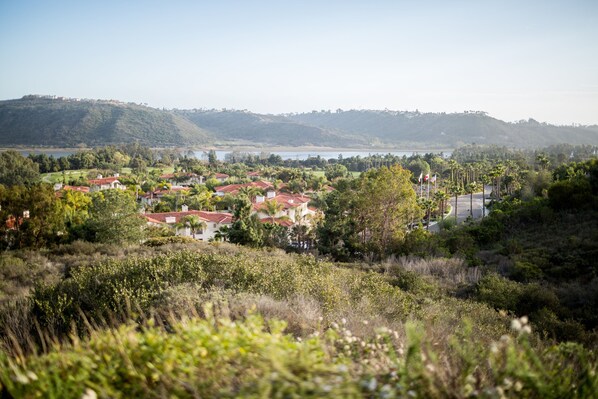 A coastal town with red-roofed houses, a clear view of the sea, and hills in the background.