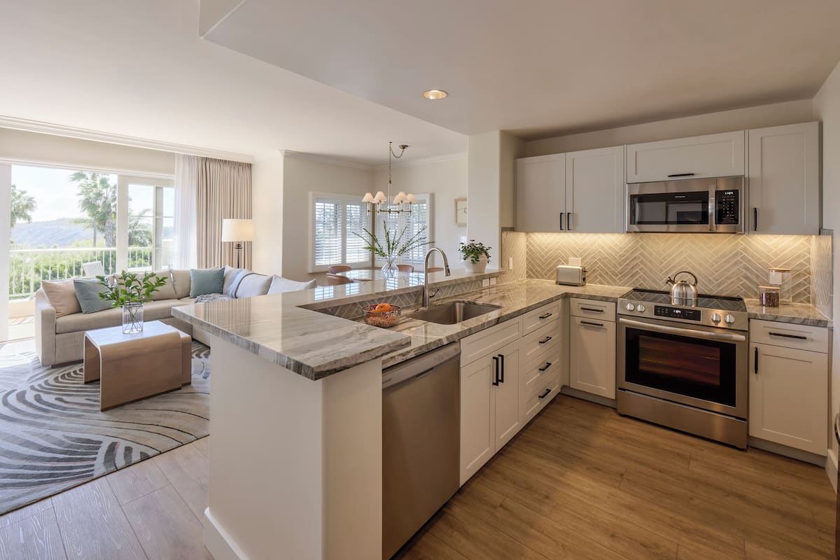 A modern kitchen with a central island, stainless steel appliances, and a dining area with a sofa and coffee table.