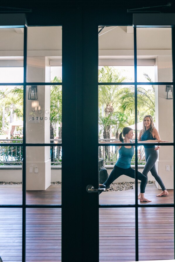 Un gimnasio con un ventanal grande, piso de madera y equipo de ejercicio.