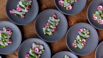 Varios platos grises con un plato de mariscos, dispuestos sobre una superficie de madera.