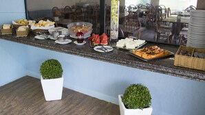 A buffet setup with various food items, including bread, fruits, and a decorative vase. - Hotel Parque das Águas (Aracaju)