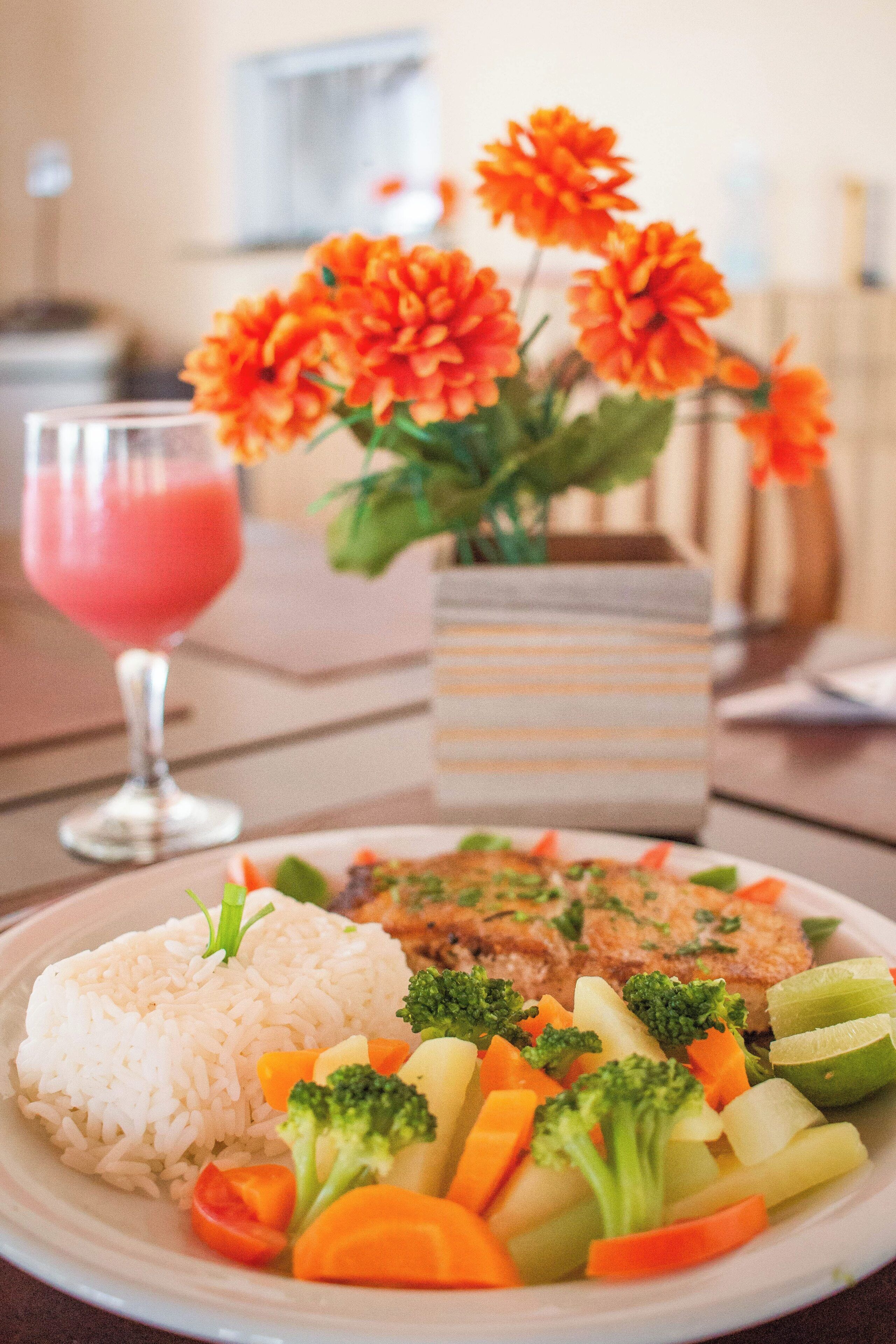 Un plato de comida con arroz, verduras y un vaso de bebida.