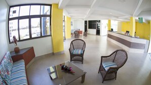 A spacious lobby with a reception desk, wicker chairs, a sofa, and a glass coffee table. - Hotel Parque das Águas (Aracaju)