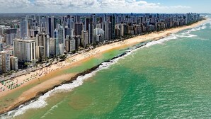 A coastal cityscape with a long beachfront lined with high-rise buildings. - Dublê Hotel (Recife)