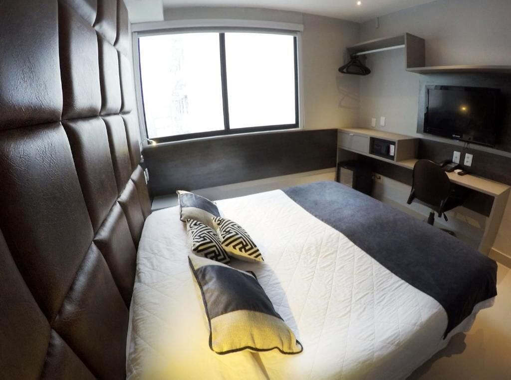 Una habitación de hotel moderna con una cama grande, un escritorio y una televisión.