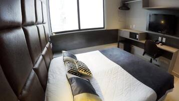 Una habitación de hotel moderna con una cama grande, un escritorio y una televisión.