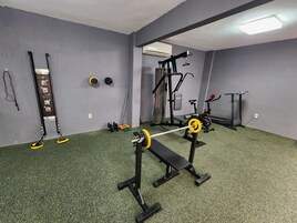 Un gimnasio con barra de dominadas, banco de pesas y diverso equipamiento de ejercicio.
