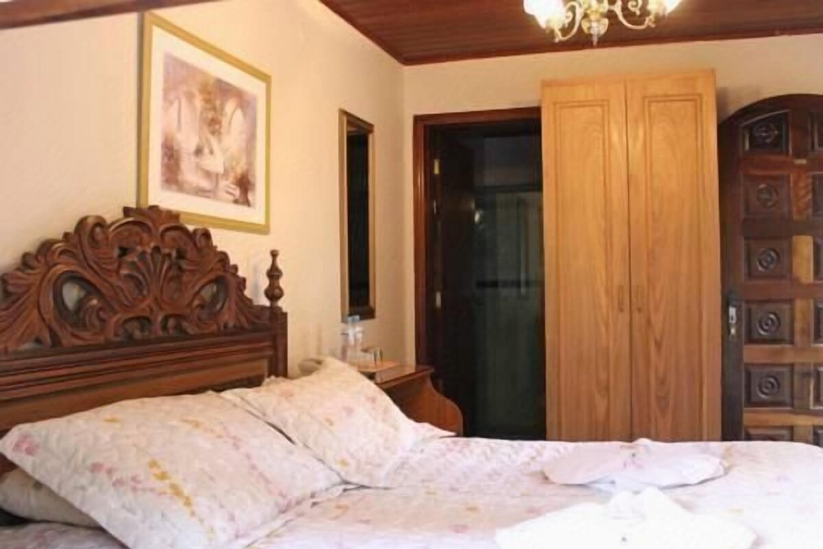 A bedroom with a wooden bed, a wardrobe, and a door.