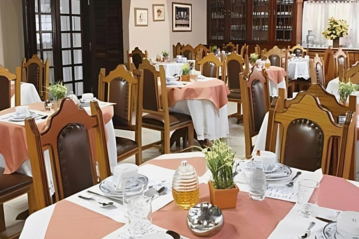 A dining area with round tables, chairs, and a variety of table settings including plates, glasses, and cutlery.