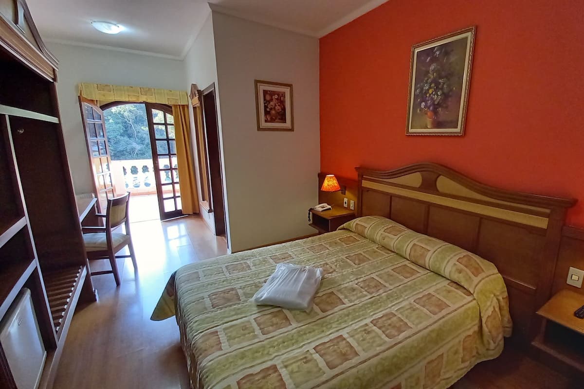 Una habitación de hotel con cama, lámparas de noche, mesita de noche, escritorio y silla.