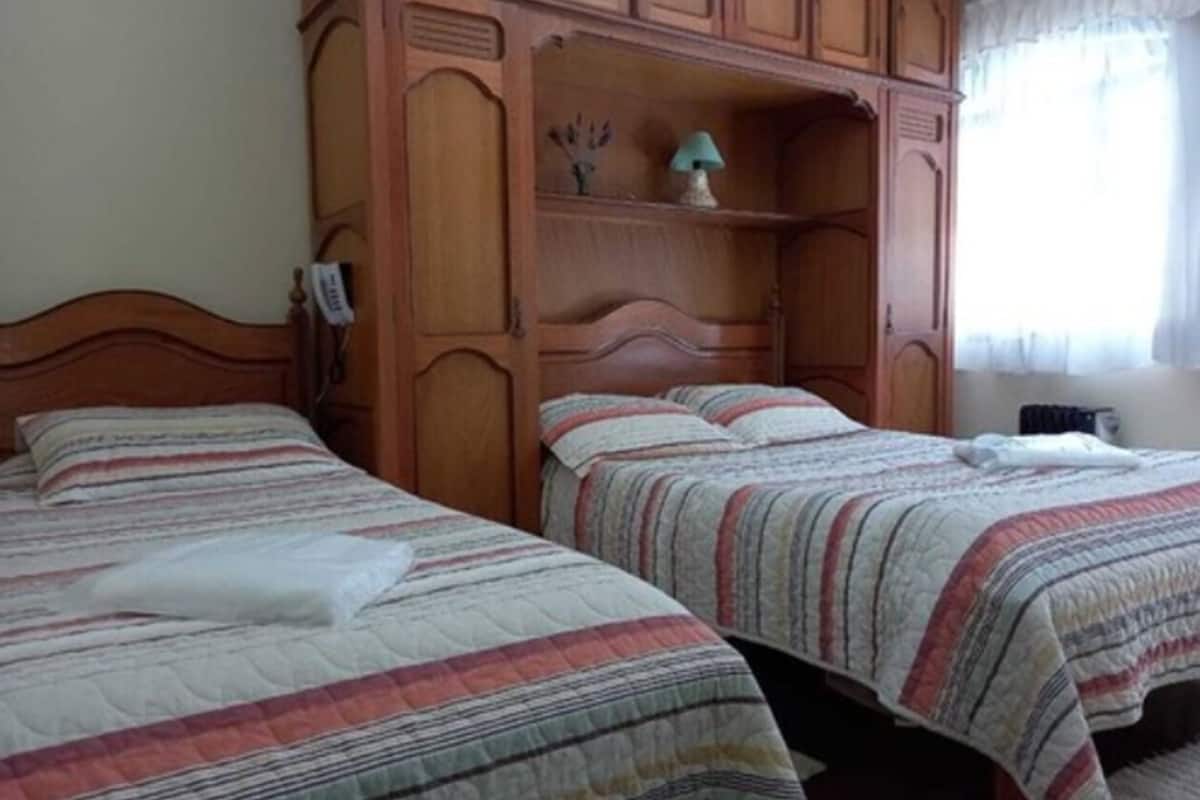 Un dormitorio con dos camas, un armario de madera y una mesita de noche.