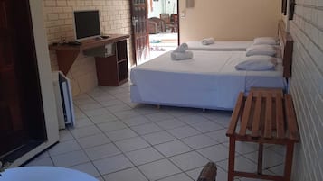 Habitación de hotel con dos camas, un escritorio con una computadora, un televisor y un banco de madera.