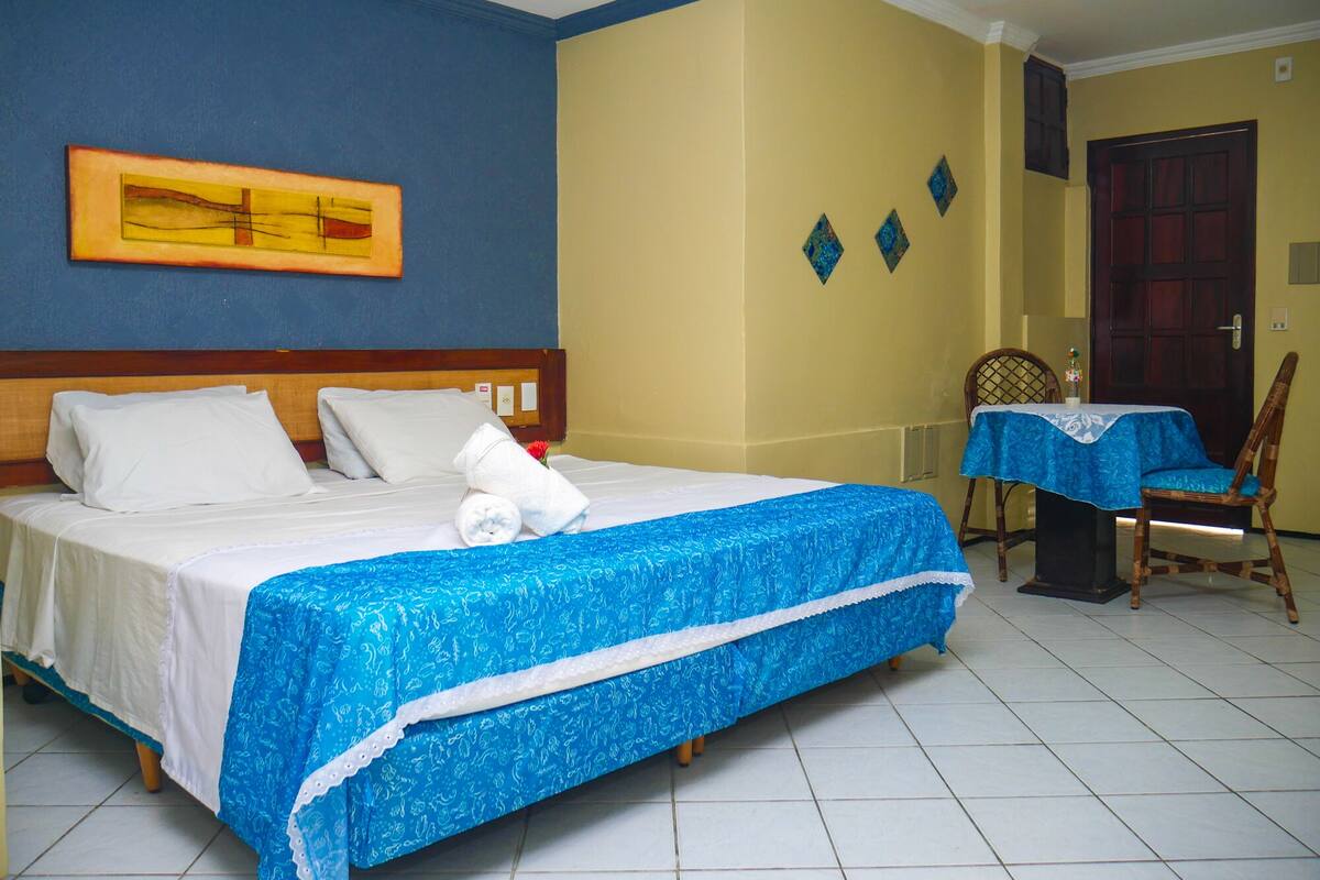 Ein Hotelzimmer mit Bett, Tisch mit Tischdecke, Stuhl und Tür.