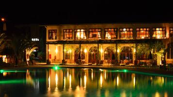 Una piscina techada, una piscina al aire libre, sombrillas